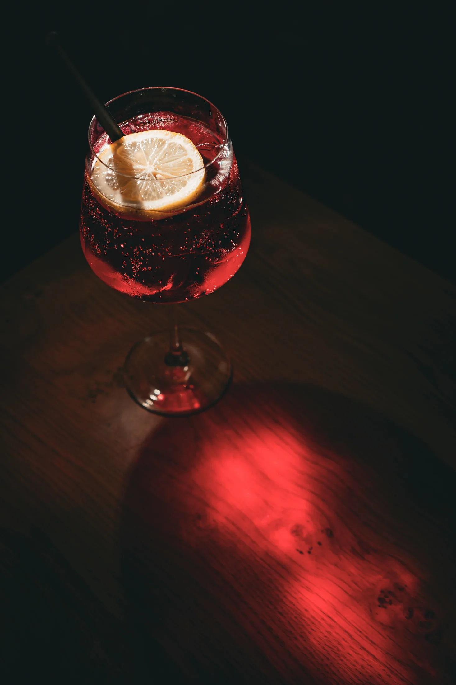 A dark red cocktail lit by the table glow