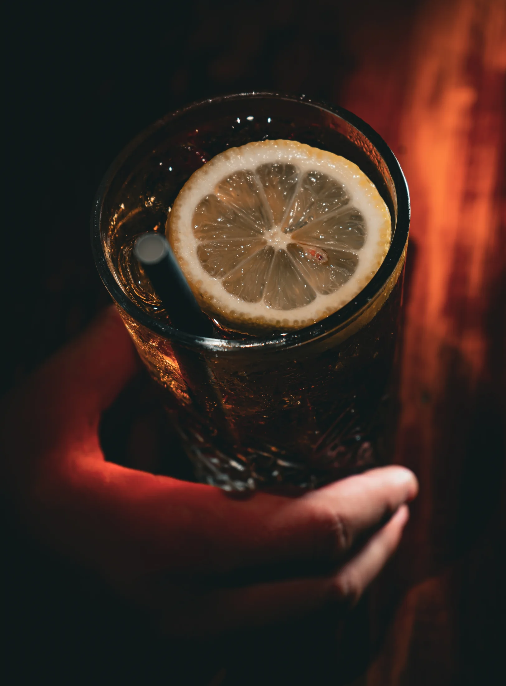 A dark cocktail garnished with lemon